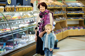 Adult woman with child choosing dessert while shopping in supermarket
