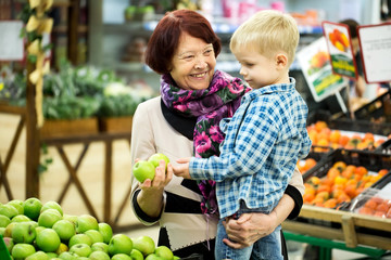 Grandmother and grandson choosing Apple fruit during shopping at vegetable supermarket