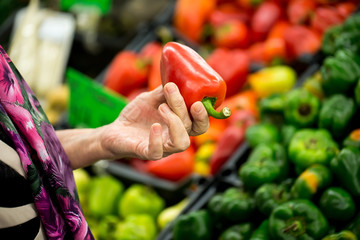 Grandma, the old woman chooses pepper in the supermarket. hands