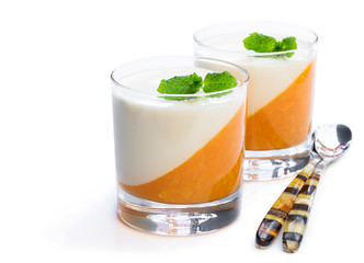 Panna cotta with orange jelly in clear glass isolated on white