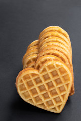 Stacks of heart shaped waffles on black background