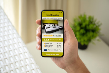 man hand holding phone with app hotel booking on screen