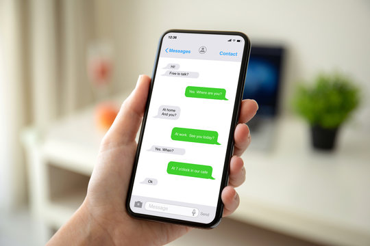 female hands holding phone with app messenger on the screen