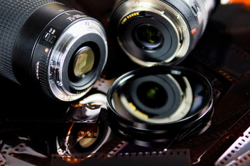 Close up of two camera lenses with isolated circular filter on negative film strips