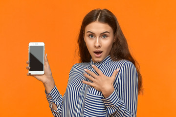 Omg. Wow. Picture of fashionable emotional young European woman opening mouth widely, holding hand...
