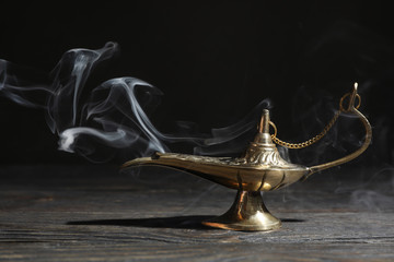 Magic Aladdin Lamp on wooden table against dark background