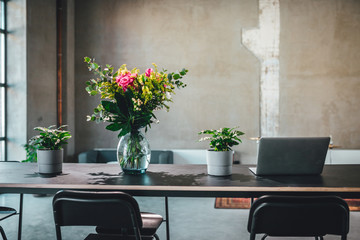 Working table with flowers and laptop in industrial environment