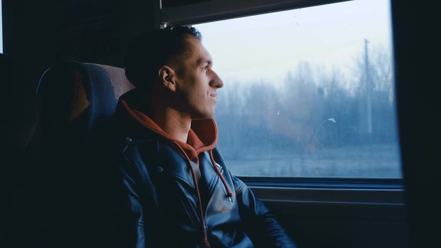 Happy Man is Looking by the Window at Sunset during Traveling by Train