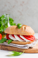 Caprese sandwich: Mozzarella, tomatoes, basil leafes, italian bread, olive oil. Olive oil bottle. white background