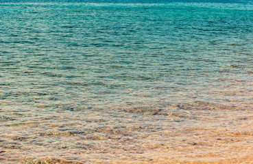 bright transparent blue water with slightly view on a stone bottom near waterfront shoreline perspective natural scenic landscape background, summer vacation and travel concept photography, copy space