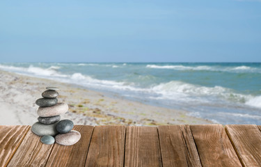 Fototapeta na wymiar Stacked zen stones on wooden pier against seascape, space for text