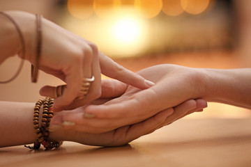 Chiromancer reading lines on woman's palm at table, closeup