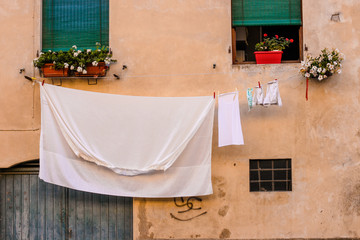 Windows, flower pots, drying clothes and linen on the typical italian street 