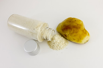 Amber powder in a clear bottle. Used for processing amber stones. Comosite with amber powder and large amber stones on bulom background