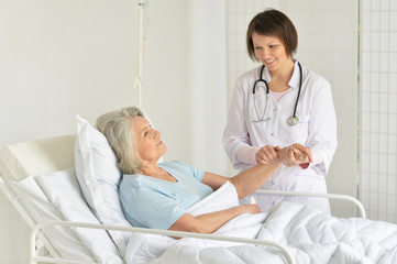 Portrait of smiling senior woman in hospital with caring doctor
