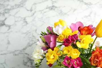 Beautiful spring freesia flowers on marble background, top view. Space for text