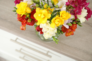 Beautiful spring freesia flowers on chest of drawers, closeup