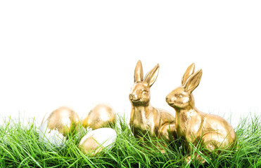 Golden rabbits Easter eggs green grass white background