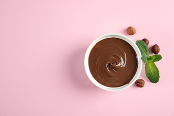 Dessert bowl with sweet chocolate cream, hazelnuts and mint on color background, top view. Space...