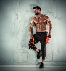 Muscular Men During his Cardio Workout with Jump Rope. He is holding his protein drink , energy...