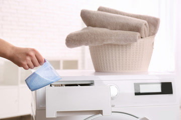 Woman pouring powder into drawer of washing machine indoors, closeup. Laundry day