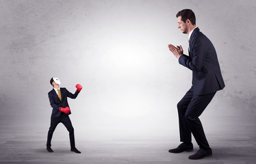 Obraz premium Big businessman being afraid of small masked businessman with box gloves in an empty room concept 