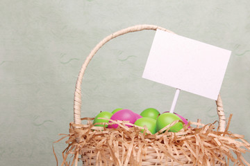 Wicker basket full of colorful easter eggss and a blank card