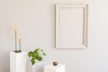 Scandi and design home decor with mock up gray poster frame, white and grey pedestals with stylish accessories, lamp and plants in pot. Stylish and minimalistic room interior. Template. Blank.
