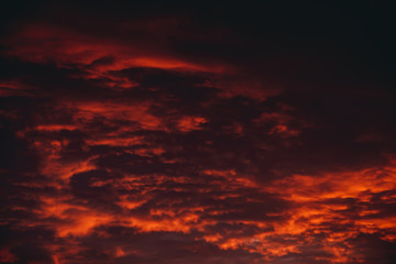 Fiery red blood vampire dawn. Amazing warm dramatic fire cloudy sky. Vivid orange sunlight. Atmospheric background of sunrise in overcast weather. Hard cloudiness. Storm clouds warning. Copy space.