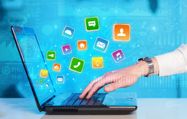 Hand using laptop with bouncing colorful application and global reports and graphs concept
