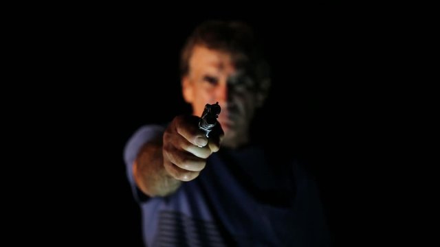 Thug pointing a gun into a camera. Concept assault or murder.