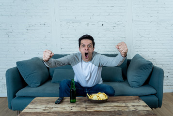 Excited young man sitting on the couch watching football. Sports supporters and fans concept
