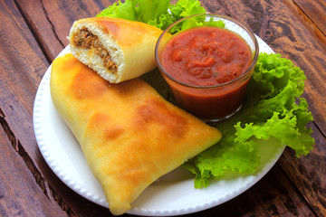 meat esfiha (sfiha) of Arab origin traditionally adapted for the Brazilian cuisine on plate on rustic wooden table