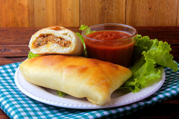 meat esfiha (sfiha) of Arab origin traditionally adapted for the Brazilian cuisine on plate on rustic wooden table