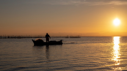 Man fishing in a boat at sunset in Albufera of Valencia.