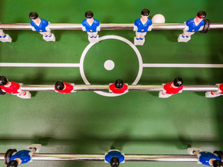 Friends having fun together playing foosball. Colleagues playing table football on break. Office people enjoying table soccer game. Close up of table football kicker game