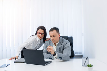 Obraz premium Two successful young people checking informations on the laptop while being in the modern office.