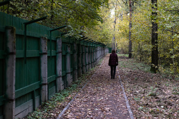 A track along a prison fence. Man walking down the path past the barbed wire.
