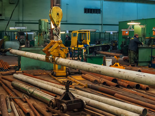 Industrial bridge crane hoisting steel pipe in metalworking factory