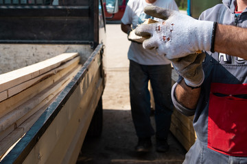 Construction workers holding loading material planks by the truck ready to delivery to the construction site