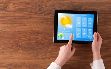 Man hand checking weekly weather forecast on tablet
