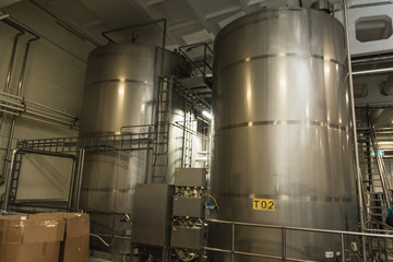 large metal cistern reservoir at the factory. industrial production of alcohol and juices. Stainless steel brewing equipment: large tanks and containers of a modern brewery. Beer production concept 