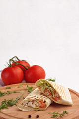 Shawarma in pita and natural organic tomatoes with greens, on a wooden background