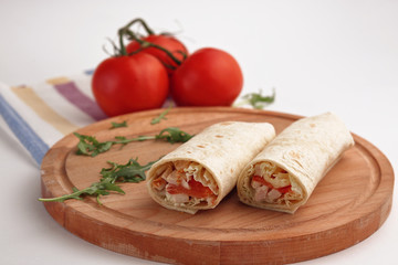 Shawarma in pita and natural organic tomatoes with greens, on a wooden background