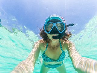woman taking an underwater selfie while snorkeling in crystal clear tropical water