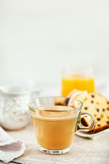 Continental breakfast table with cup of hot  coffee with milk, cakes and orange juice