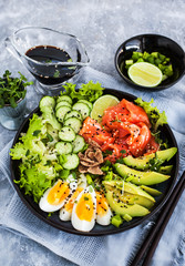 Salmon poke bowl served with avocado, eggs, cucumber and greens