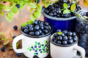 Fresh ripe bluberries (bilberries) in enamel mugs