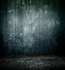 Empty dark room interior with old mottled doodles concrete wall and dirty wooden floor for background texture.