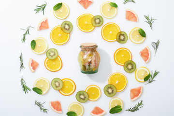 flat lay with fresh sliced kiwi, oranges, lemons, grapefruits, mint, rosemary and detox drink in jar